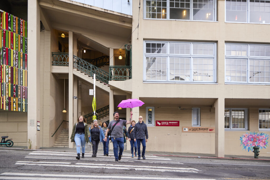 Tour guide Matt Bentley holds the Savor Seattle Tours pink umbrella while conducting a pike place market food tour