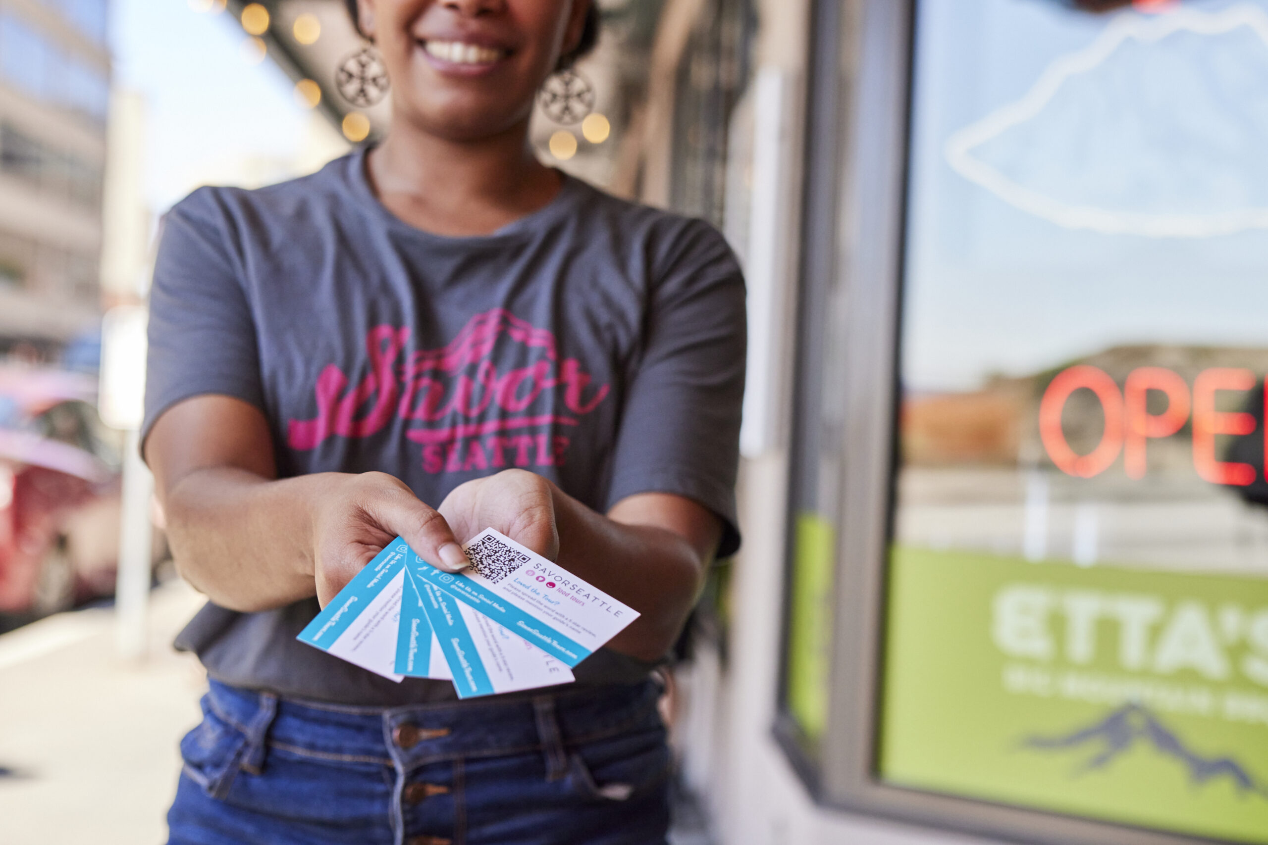 A Savor Seattle tour guide holds up tickets to a Pike Place Market Food Tour