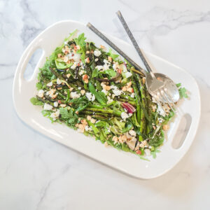 A white platter on a white marble countertop, with Asparagus & Spring Onion Salad in it. The best of Seattle Food Tours!